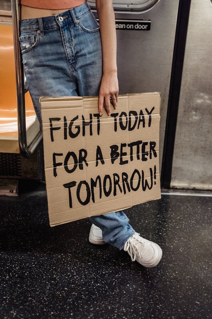 About A person holding a protest sign in a subway advocating for a better future.